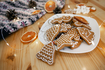 Delicious homemade Christmas cookies on a plate with garland and oranges. Spirit of the new year