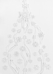 White wooden snowflakes, small Christmas trees, round beads on narrow ribbons laid out flat lay as creative Xmas tree.