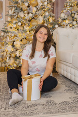 
young woman with christmas present near the christmas tree