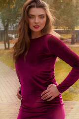 Obraz premium Brunette in autumn Park and autumn leaves. Autumn mood. Yellow, red and green leaves. Burgundy dress
