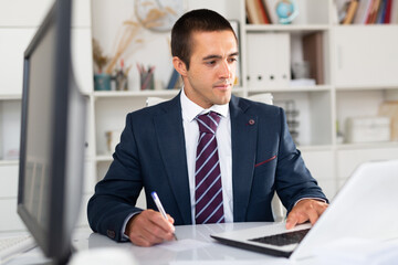 Successful businessman working with papers and laptop in office