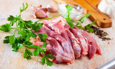 Raw turkey thigh chopped on wooden board with herbs and garlic