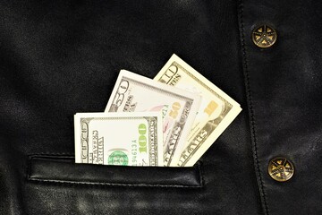 Money in the pocket of a leather vest. Us dollars are cash for in-store shopping.