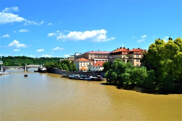 Fototapeta na wymiar Vltava River during sunny day. Vltava River photos from Charles Bridge, Prague, Czech Republic. Blue sky and yellow river together in same photo.