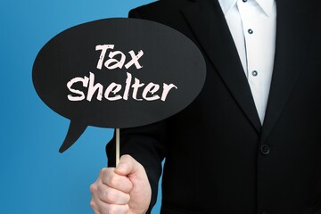 Tax Shelter. Businessman holds speech bubble in his hand. Handwritten Word/Text on sign.