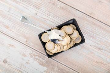 Small plate full of euro coins and a spoon on the table
