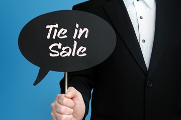 Tie in Sale. Businessman holds speech bubble in his hand. Handwritten Word/Text on sign.