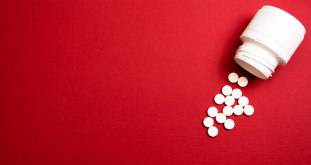 White round tablets scattered in front of plastic container of pills