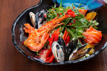 Seafood salad: shrimp, mussels and salmon, arugula and oranges. In a decorative plate