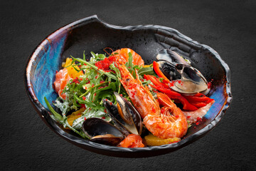 Seafood salad: shrimp, mussels and salmon, arugula and oranges. In a decorative plate