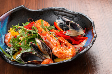 Seafood salad: shrimp, mussels and salmon, arugula and oranges. In a decorative plate
