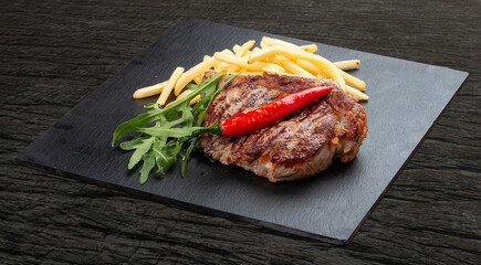 Pork steak with French fries and red sauce on a stone board