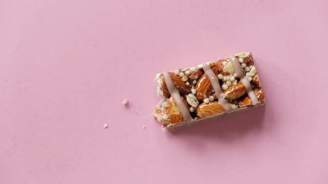 Protein Almond Granola Bar On Pink Background. Eating Bite By Bite Stop Motion Animation. Sport Diet Fitness Food Concept