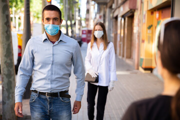 Fototapeta na wymiar Young people in protective face mask for virus disease prevention walking on summer city street during pandemic situation