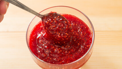 Jam from raspberries with sugar on wooden background..