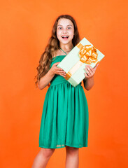 Fototapeta premium In shopping store. Black Friday sale. holidays concept. international childrens day. Joyous female kid holding gift-wrapped box. Holding gift in hand. Smiling little girl with shopping gift