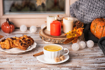Hot tea and pastries with pecan on the sill window, rainy weather outside. Autumn seasonal decor composition with candles light. Cozy home concept.