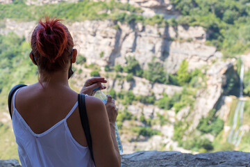 De espalda, mujer con botella de agua mirando el paisaje