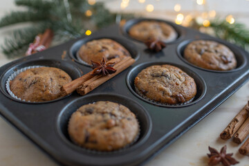 Fresh homemade gingerbread muffins in baking form on wooden table with Christmas decoration