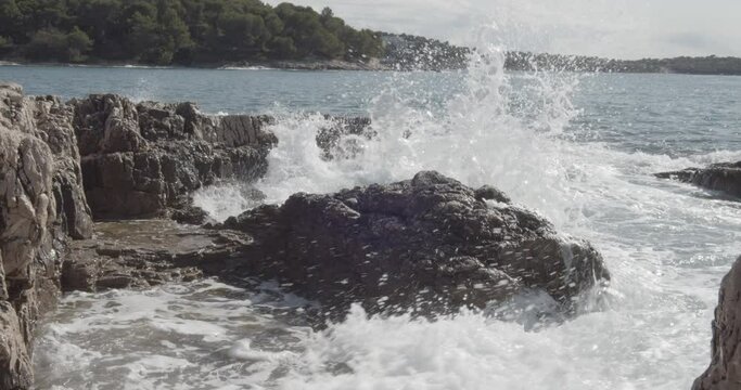 Croatian ocean Seascape scene with waves breaking on volcanic grey rocks on the coastal line of Pula.