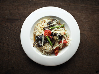 SOM TUM, Thai spicy green papaya salad with preserved crab on wooden table