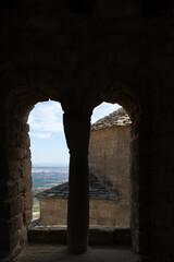 there is a backlight looking through the double arched window in the old cold stone room of the medieval castle
