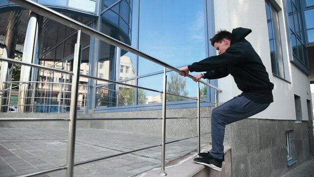 Young man running and doing parkour trick in the city at daytime.