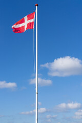 Flagpole against a blue sky with the flag of Denmark