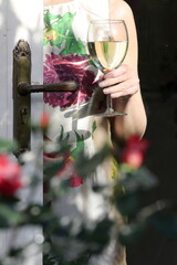 Mature woman holding a glass of white wine as seen through patio glass door