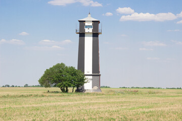 Black and white lighthouse stands on clear field. summer wallaper