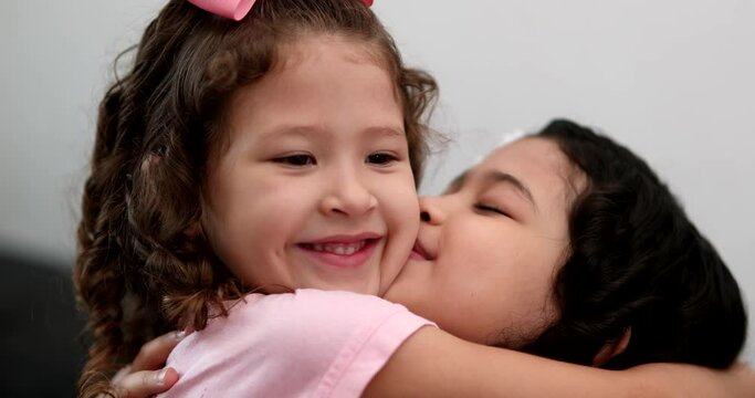 Little girl kissing and hugging sibling sister, family love affection