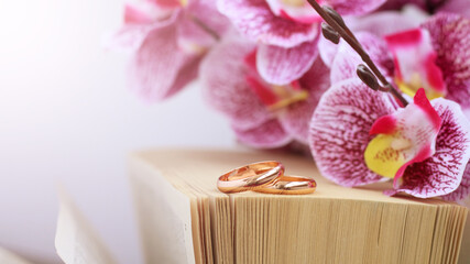 bouquet of pink flowers, wedding rings and a book