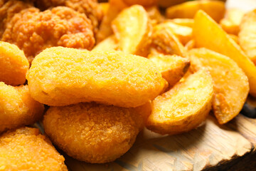 Tasty fried chicken nuggets on serving board, closeup