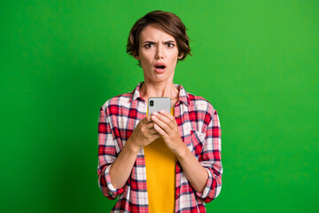 Portrait of attractive lady disbelief open mouth sullen face plaid outfit isolated on green color...
