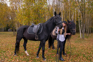 A young slender girl with blonde hair leads two horses .