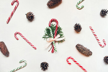 White wooden background with red and green christmas candies and conifer cones