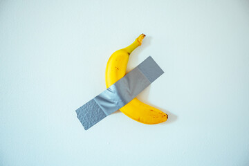 A banana taped to the white wall.