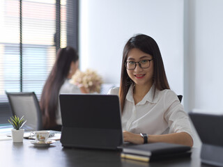 Female office worker looking into camera while working in office room