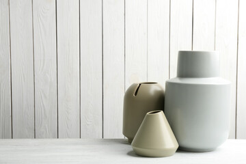 Stylish ceramic vases on white wooden table. Space for text