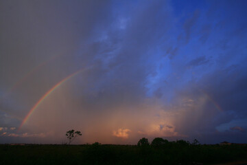 Naklejka na ściany i meble Twilight with a rainbow against a background of clouds and blue sky