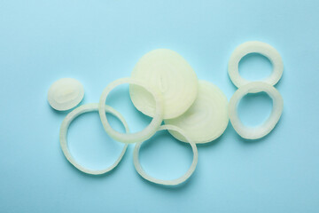 Fresh onion slices on blue background, top view