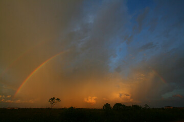 Twilight with a rainbow against a background of orange clouds and blue sky
