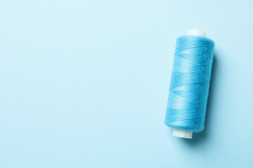 Blue sewing thread on blue background, space for text