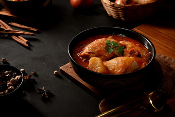 Close up view of chicken Massaman Curry soup with ingredients on kitchen table