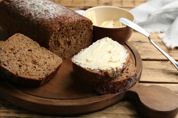Tasty freshly baked bread with butter on wooden table