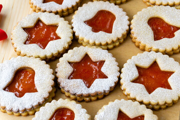 Christmas or new year linzer cookies in the shape of stars and bells with jam on a wooden background