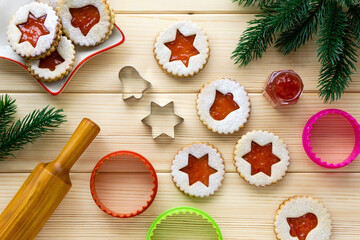 Christmas linzer biscuits with cookie cutters and rolling pin on a wooden table