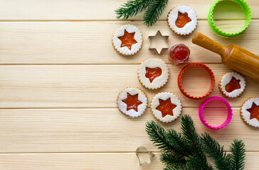 Christmas linzer biscuits with cookie cutters and rolling pin on a wooden table. Space for text