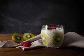 kiwi and raspberry porridge with oat milk and chia seeds on brown wooden table
