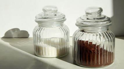 two glass jars with ground coffee and sugar on the table